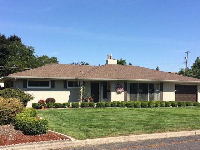 ranch-style house featuring a garage, a chimney, a front lawn, and roof with shingles