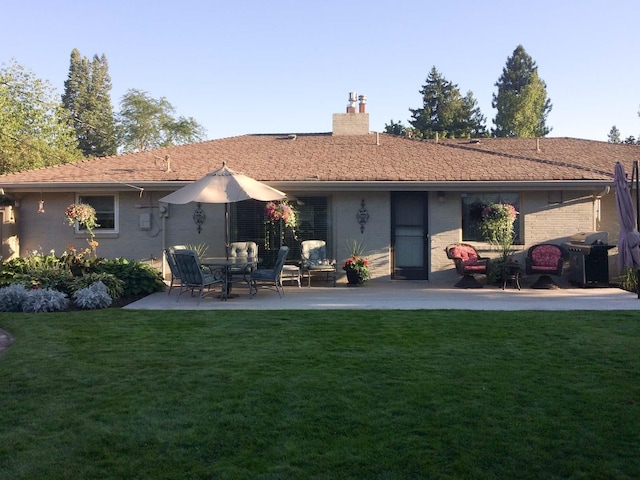 back of house featuring a patio area, a yard, a chimney, and brick siding