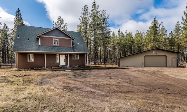 view of front of house featuring a garage, an outdoor structure, driveway, and a shingled roof