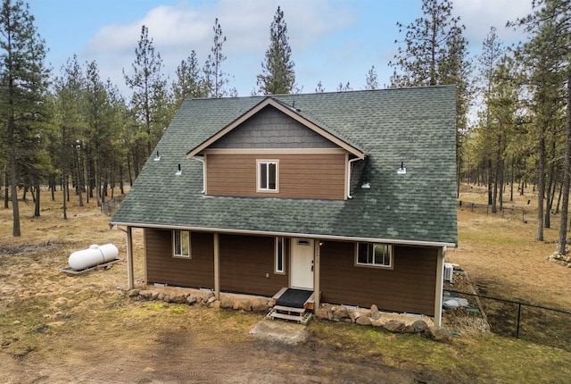 chalet / cabin featuring roof with shingles and fence