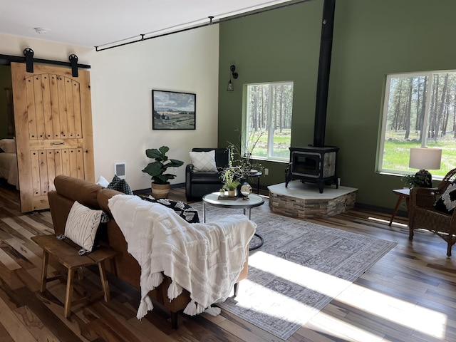 living room with a barn door, a wood stove, and wood finished floors