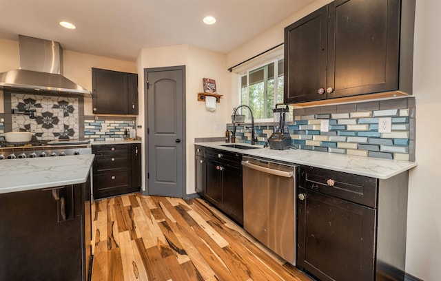 kitchen featuring decorative backsplash, stainless steel dishwasher, a sink, light wood finished floors, and wall chimney exhaust hood