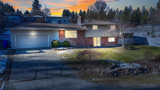 view of front of house featuring brick siding, a chimney, a lawn, an attached garage, and driveway