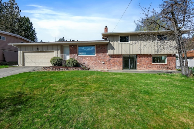 split level home with board and batten siding, driveway, a front yard, and a garage