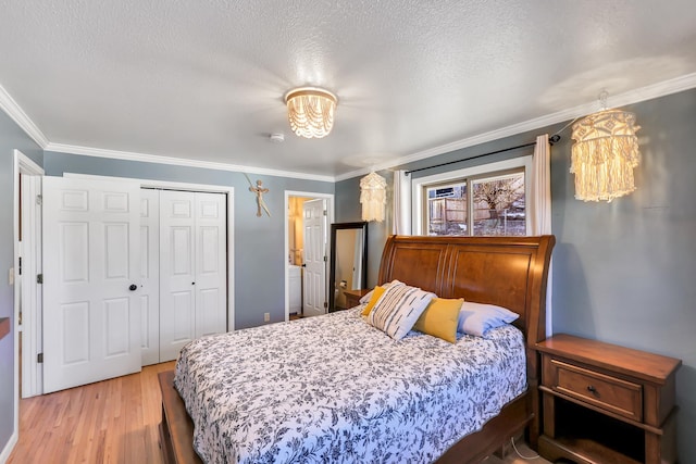 bedroom featuring light wood finished floors, ornamental molding, a textured ceiling, a chandelier, and a closet