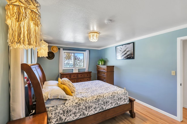 bedroom featuring a textured ceiling, ornamental molding, wood finished floors, and baseboards