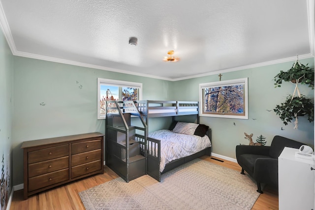 bedroom with a textured ceiling, ornamental molding, and light wood-type flooring