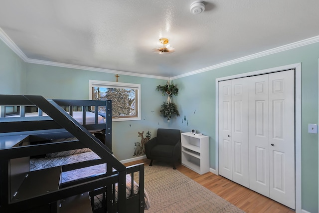 bedroom with light wood-style floors, a closet, ornamental molding, and baseboards