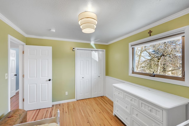 interior space featuring light wood finished floors, a closet, ornamental molding, a textured ceiling, and baseboards