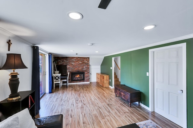 living room featuring stairs, a fireplace, wood finished floors, and crown molding