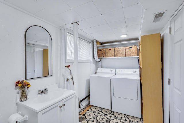 washroom with a sink, laundry area, washing machine and clothes dryer, and visible vents