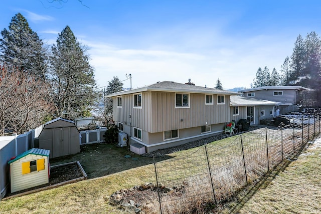 back of house featuring a yard, a fenced backyard, an outdoor structure, and a storage unit