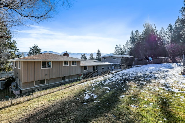 rear view of house featuring a chimney and fence