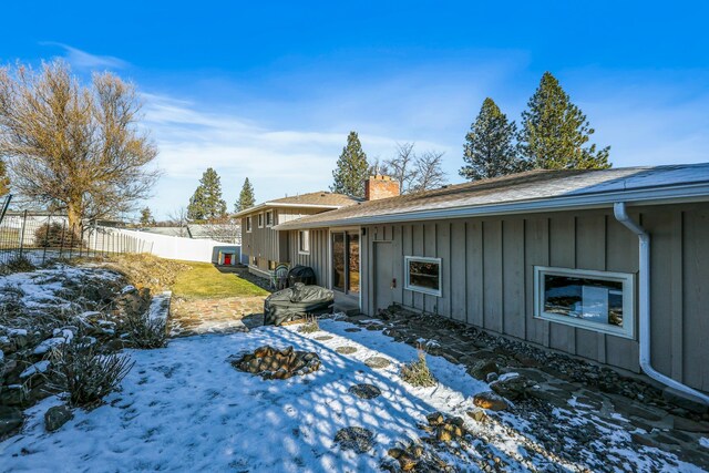 exterior space featuring a chimney, fence, and board and batten siding