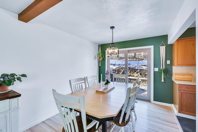 dining area with a chandelier, beam ceiling, light wood-style flooring, and baseboards