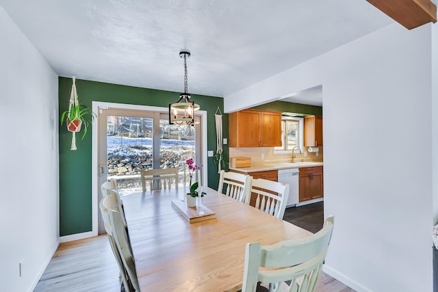 dining area with light wood-type flooring, baseboards, and a wealth of natural light