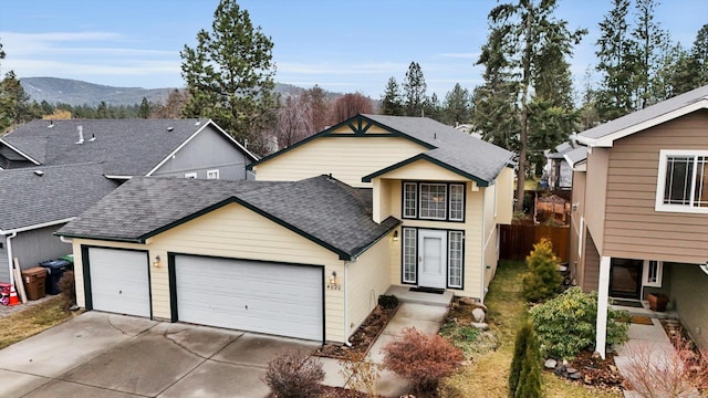 view of front of property featuring driveway, a garage, roof with shingles, fence, and a mountain view