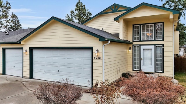 view of front of property featuring a garage, driveway, and a shingled roof