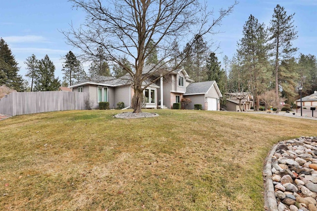 view of front of property with a front yard, fence, and an attached garage