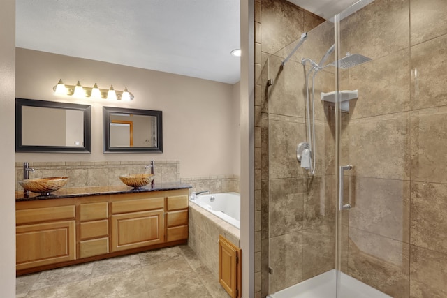 bathroom featuring a stall shower, a garden tub, a sink, and double vanity