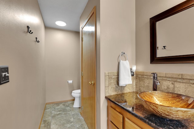 bathroom with baseboards, vanity, and toilet