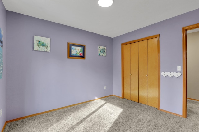 unfurnished bedroom featuring carpet floors, baseboards, and a closet