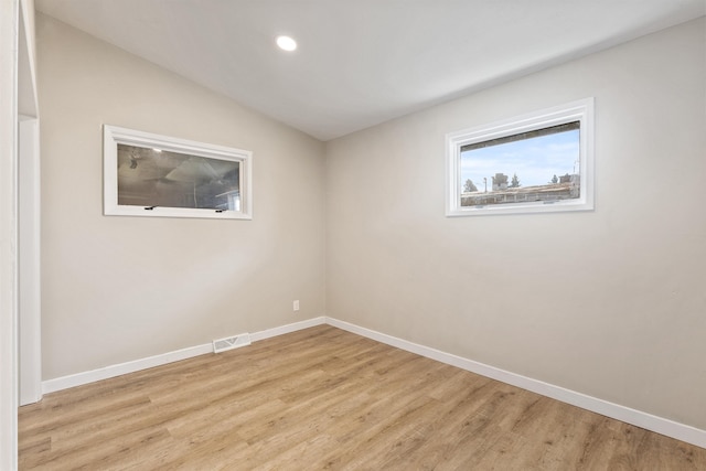 unfurnished room with lofted ceiling, baseboards, visible vents, and light wood finished floors