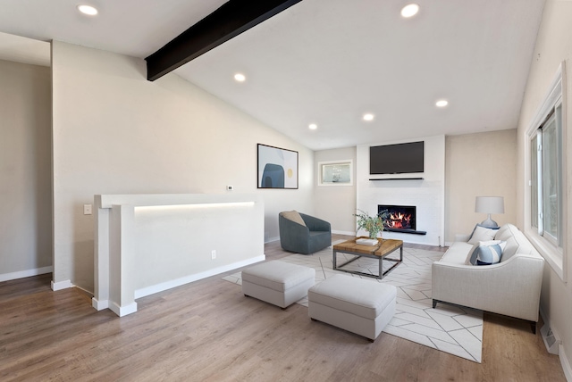 living room with recessed lighting, lofted ceiling with beams, wood finished floors, a lit fireplace, and baseboards