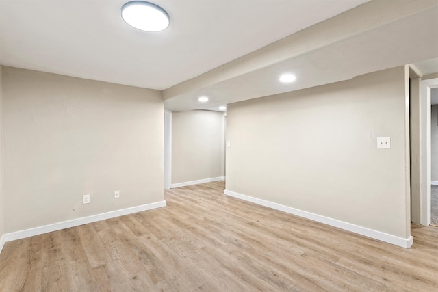 finished below grade area featuring light wood finished floors, recessed lighting, and baseboards