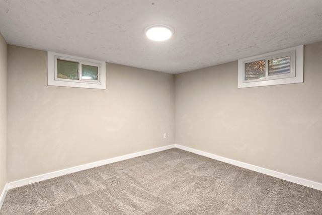 finished basement with carpet floors, a textured ceiling, and baseboards