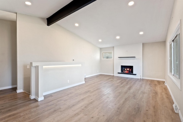 unfurnished living room featuring baseboards, wood finished floors, vaulted ceiling with beams, a lit fireplace, and recessed lighting