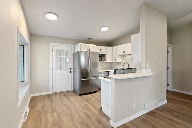 kitchen with stainless steel appliances, light countertops, visible vents, and light wood-style floors