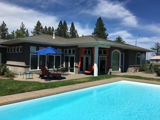 back of property with an outdoor pool and a patio