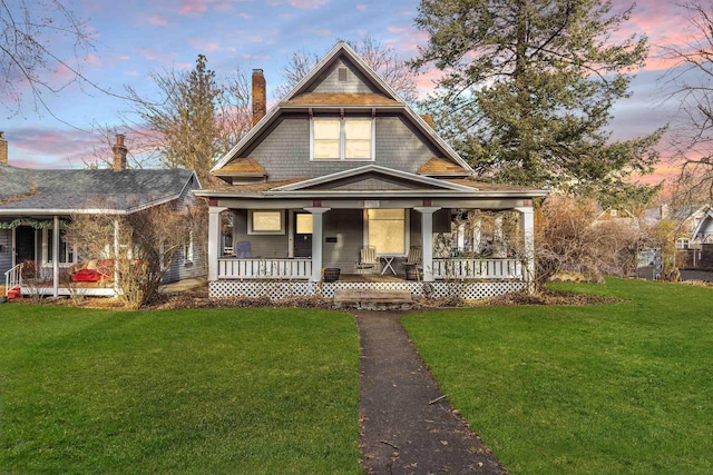 view of front of house featuring covered porch, a chimney, and a front lawn