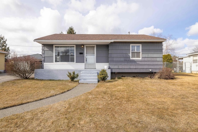 view of front of home with roof with shingles and a front lawn