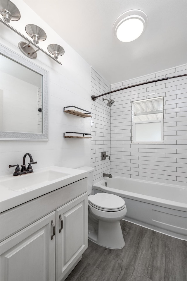 bathroom with washtub / shower combination, vanity, toilet, and wood finished floors