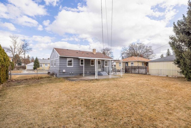 rear view of house with a patio area, a fenced backyard, a chimney, and a lawn