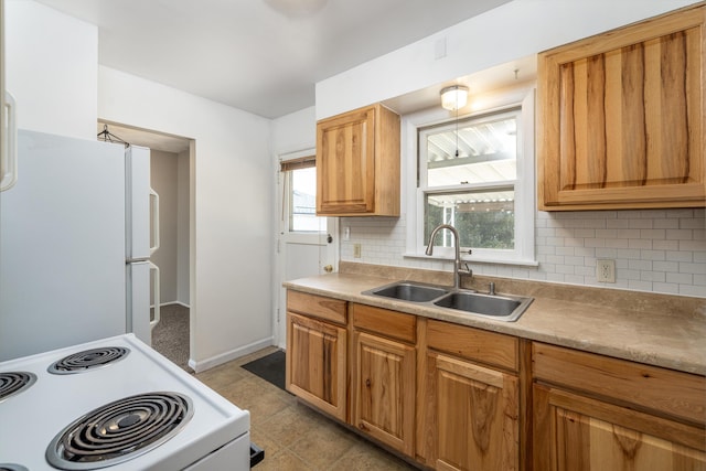 kitchen featuring light countertops, decorative backsplash, a sink, white appliances, and baseboards