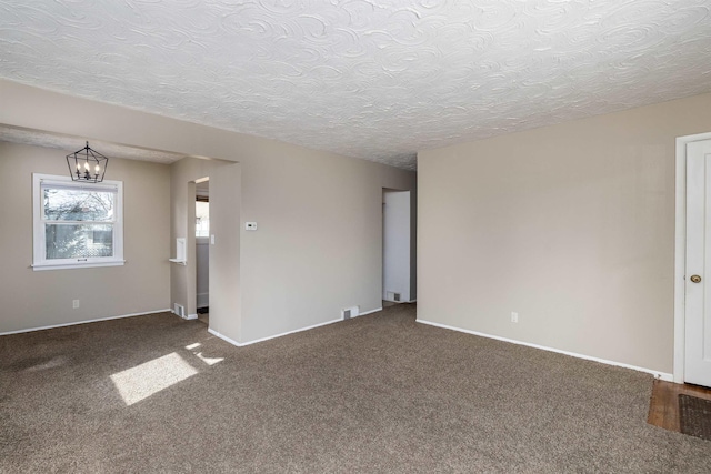 carpeted empty room featuring baseboards, a chandelier, and a textured ceiling