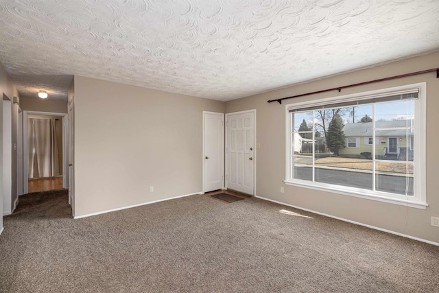 unfurnished room featuring carpet, a textured ceiling, and baseboards