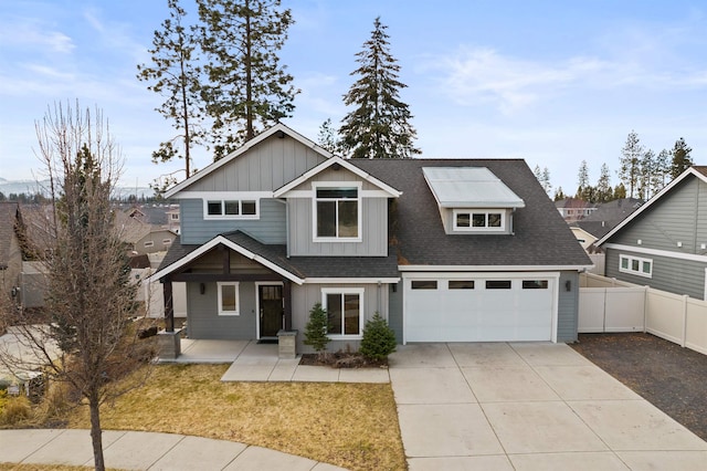 craftsman-style home with a shingled roof, concrete driveway, fence, a front lawn, and board and batten siding