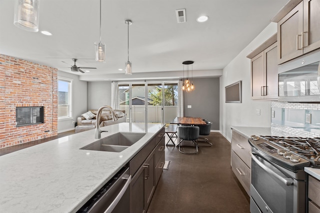 kitchen with a fireplace, a sink, visible vents, appliances with stainless steel finishes, and pendant lighting