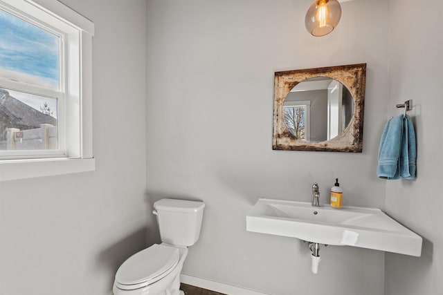 half bath featuring toilet and baseboards