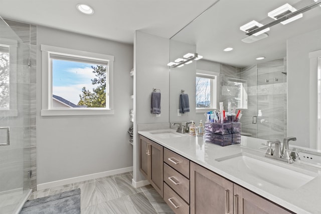 full bathroom with baseboards, double vanity, a sink, and a shower stall