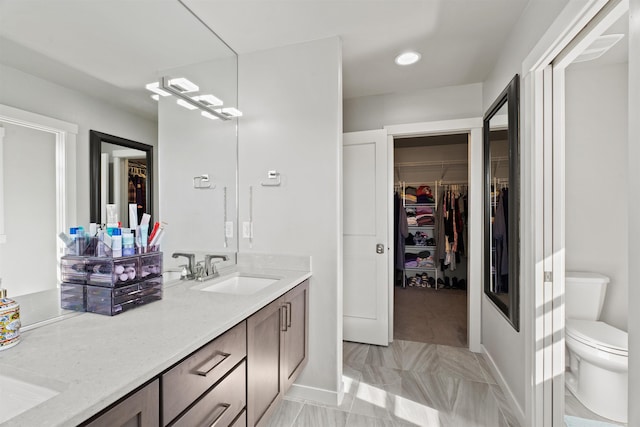 bathroom with vanity, toilet, and a spacious closet