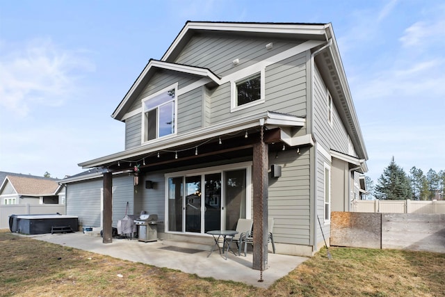 rear view of property featuring a patio, fence, and a hot tub