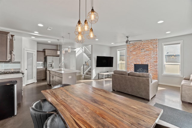 dining room with baseboards, stairway, a brick fireplace, concrete floors, and recessed lighting