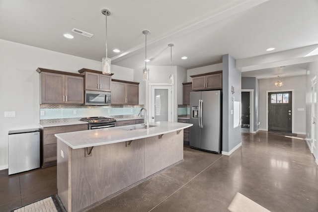 kitchen with visible vents, a sink, stainless steel appliances, a kitchen bar, and backsplash