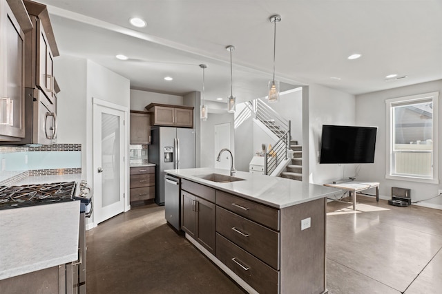 kitchen featuring appliances with stainless steel finishes, hanging light fixtures, a sink, backsplash, and recessed lighting