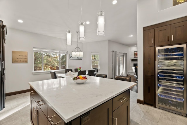 kitchen featuring a center island, beverage cooler, decorative light fixtures, and dark brown cabinets